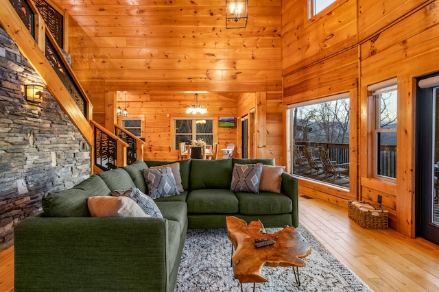 living room with an inviting chandelier, plenty of natural light, hardwood / wood-style floors, and wood walls