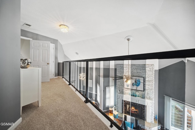 hall with baseboards, visible vents, vaulted ceiling, and carpet flooring