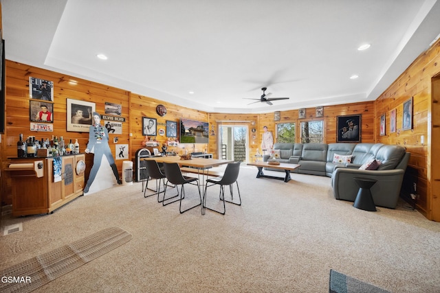 carpeted dining area with a ceiling fan, recessed lighting, visible vents, and wood walls