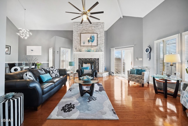 living room with a fireplace, a chandelier, wood finished floors, high vaulted ceiling, and baseboards