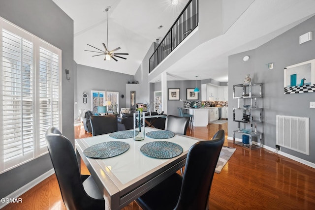 dining room with high vaulted ceiling, wood finished floors, a ceiling fan, visible vents, and baseboards