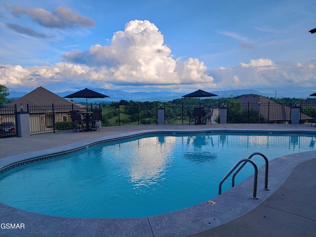 pool with fence, a mountain view, and a patio