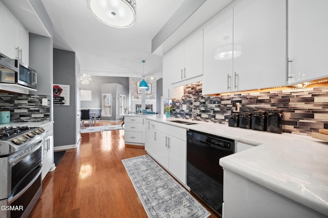 kitchen featuring wood finished floors, stainless steel appliances, a sink, and light countertops