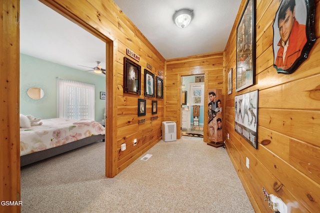 hall with carpet flooring, visible vents, and wooden walls