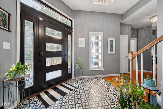 entrance foyer featuring stairs, a wealth of natural light, and baseboards