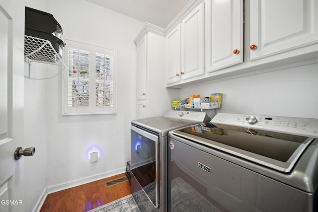 laundry room featuring cabinet space, visible vents, baseboards, washer and clothes dryer, and wood finished floors