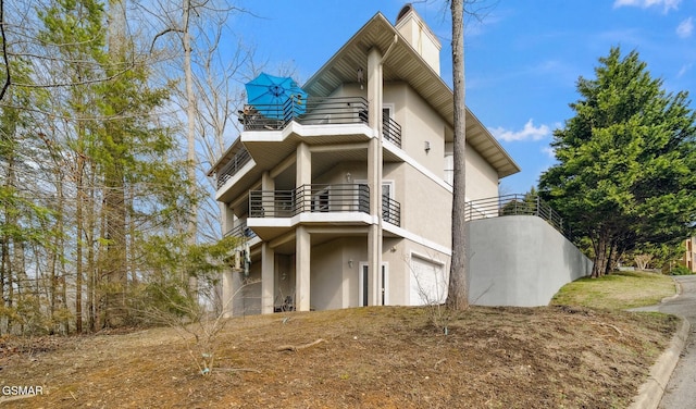 view of home's exterior featuring an attached garage, a balcony, and stucco siding