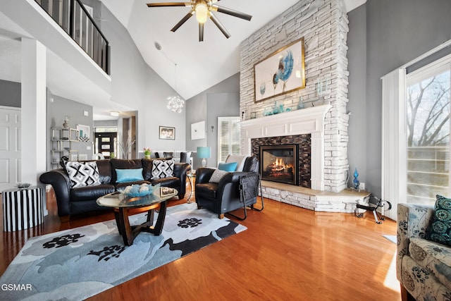 living room with a stone fireplace, a high ceiling, and wood finished floors