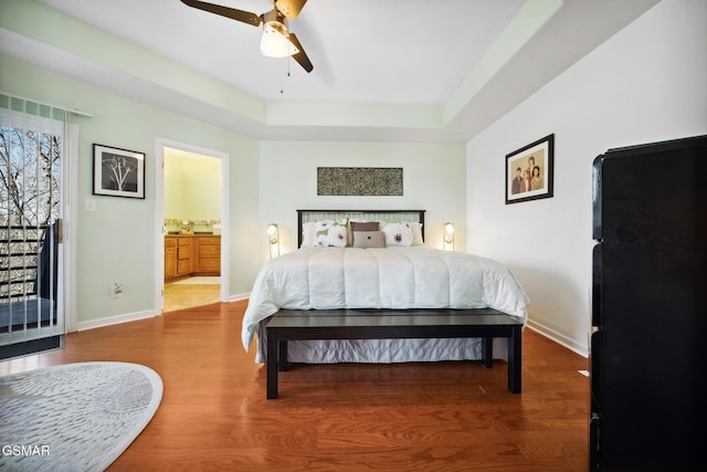 bedroom featuring ensuite bathroom, wood finished floors, a ceiling fan, and baseboards