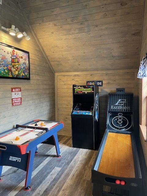 game room featuring wooden walls, dark wood-type flooring, wood ceiling, and vaulted ceiling