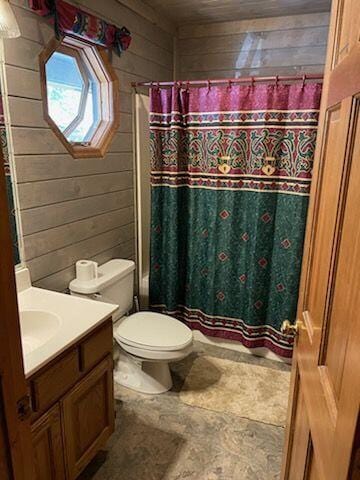 bathroom with vanity, toilet, and wooden walls