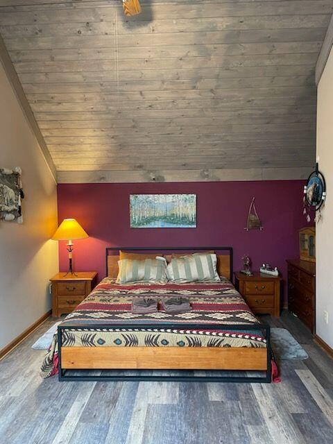 bedroom with lofted ceiling, dark hardwood / wood-style floors, and wooden ceiling