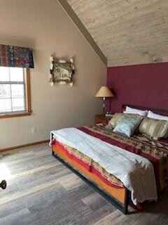 bedroom with wood-type flooring and vaulted ceiling