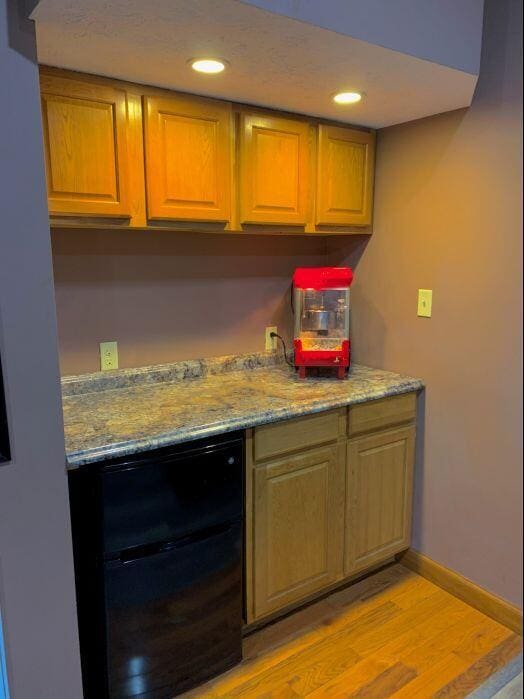 kitchen featuring light stone countertops, light wood-type flooring, and refrigerator