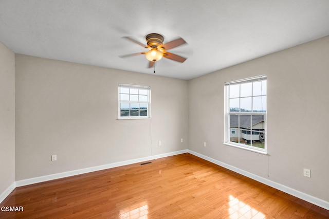 empty room featuring visible vents, plenty of natural light, a ceiling fan, and light wood finished floors