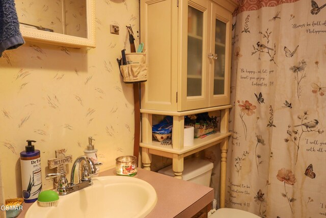 bathroom featuring toilet, wallpapered walls, a shower with curtain, and vanity