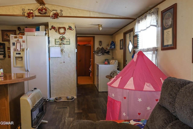 interior space featuring visible vents, dark wood finished floors, heating unit, vaulted ceiling, and washer and dryer