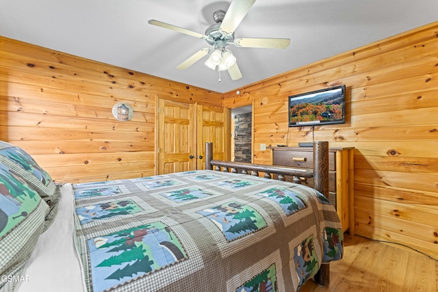 bedroom featuring ceiling fan, wood-type flooring, and wood walls