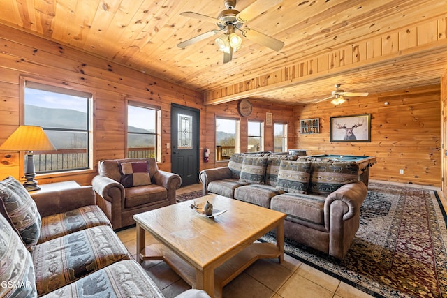 tiled living room featuring ceiling fan, wood walls, and wooden ceiling