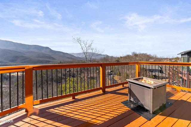 deck with a baseboard radiator, a mountain view, and an outdoor fire pit