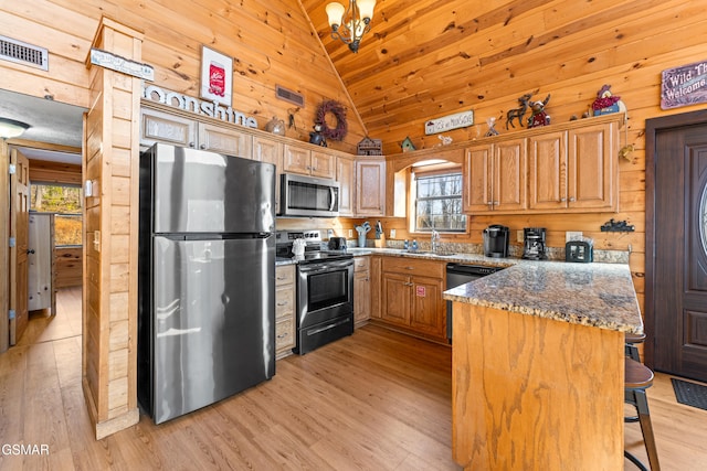 kitchen with stainless steel appliances, light hardwood / wood-style floors, vaulted ceiling, and dark stone counters