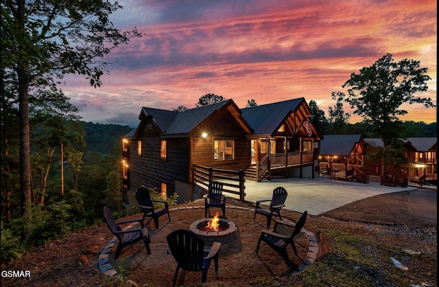 rear view of house featuring a fire pit, metal roof, a deck, driveway, and a patio