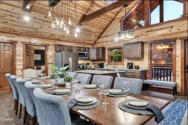 dining room with wooden walls, wood ceiling, beamed ceiling, and high vaulted ceiling