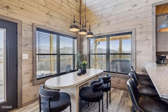 dining space with wooden walls and light wood-style flooring