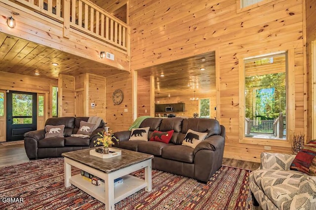 living room with a towering ceiling, plenty of natural light, and wooden walls