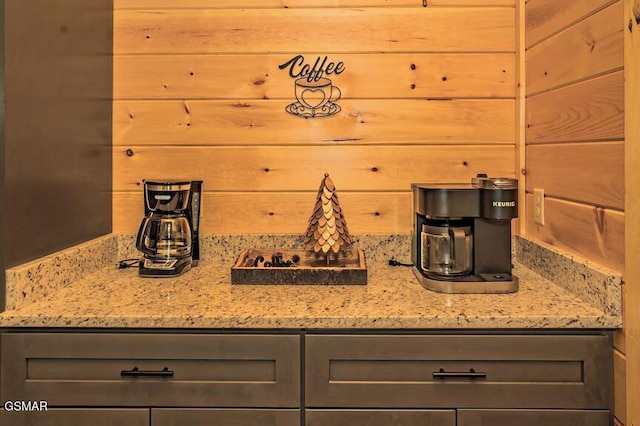 kitchen with light stone counters, wood walls, and gray cabinetry