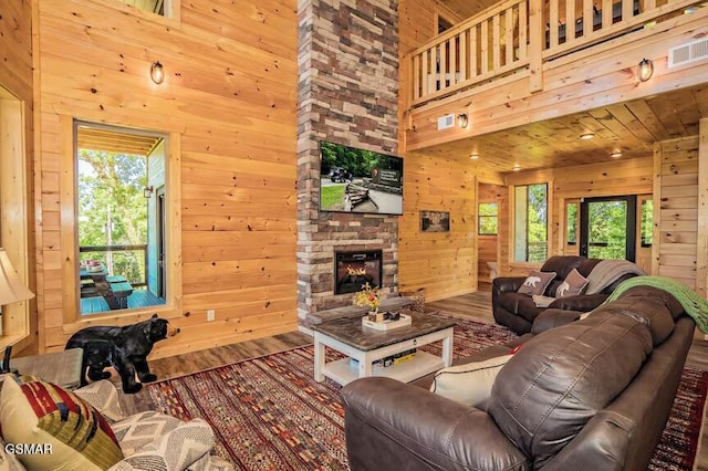 living room featuring a towering ceiling, hardwood / wood-style floors, a fireplace, and wooden walls