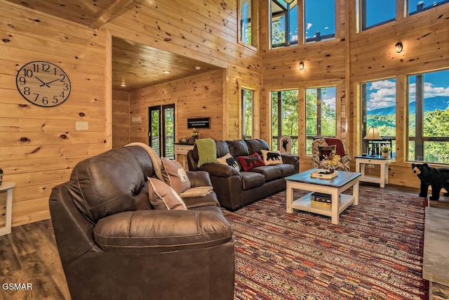 living room with dark wood-type flooring, wood walls, wooden ceiling, a mountain view, and a high ceiling