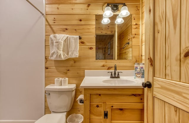 bathroom with wood walls, vanity, and toilet