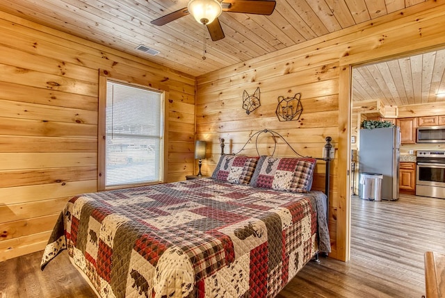 bedroom featuring wooden ceiling, wooden walls, ceiling fan, stainless steel fridge, and wood-type flooring