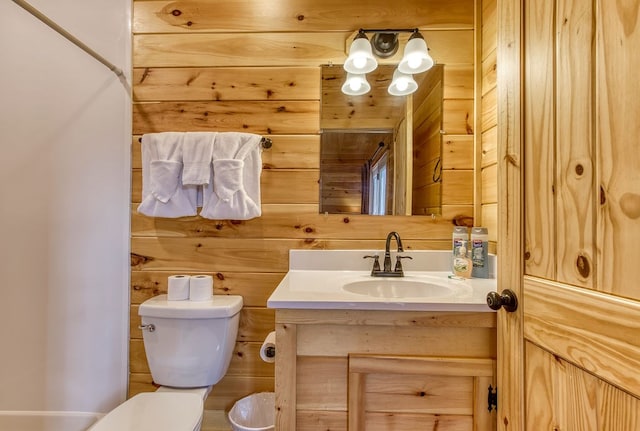 bathroom featuring vanity, toilet, and wooden walls