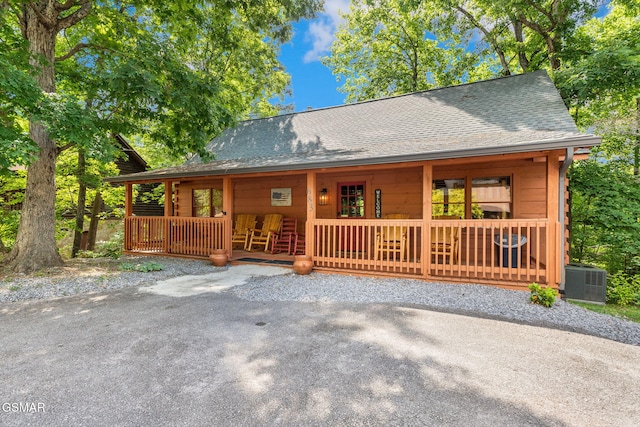 chalet / cabin featuring covered porch, roof with shingles, and central AC unit