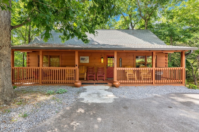 chalet / cabin featuring a shingled roof and covered porch