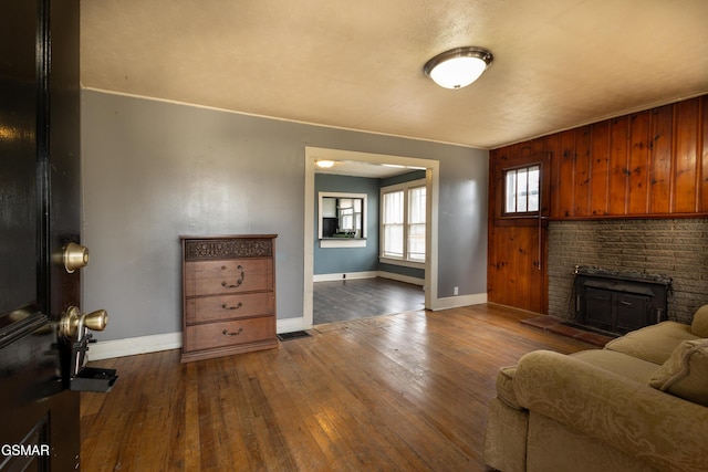 living room with dark wood-type flooring and a brick fireplace