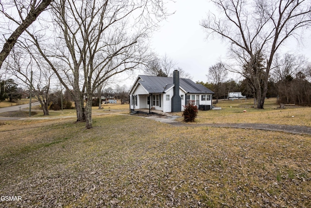 view of side of property featuring covered porch and a lawn