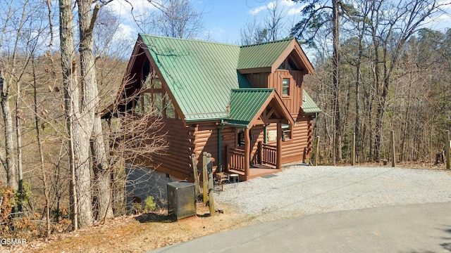 log home featuring gravel driveway, metal roof, and log exterior