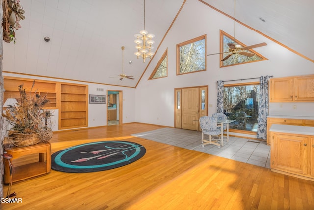 living room with built in shelves, high vaulted ceiling, ceiling fan, and light wood-type flooring