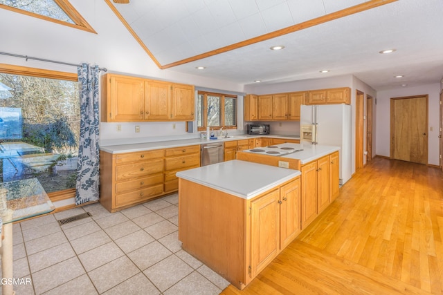 kitchen featuring vaulted ceiling, sink, light wood-type flooring, a center island, and white appliances