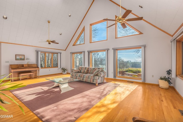 living room with ceiling fan, ornamental molding, high vaulted ceiling, and light wood-type flooring