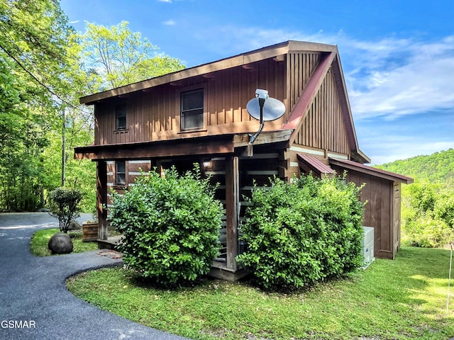 exterior space with board and batten siding and a front yard