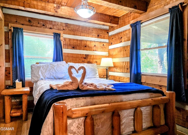 bedroom with wooden walls, wooden ceiling, beam ceiling, and wood finished floors