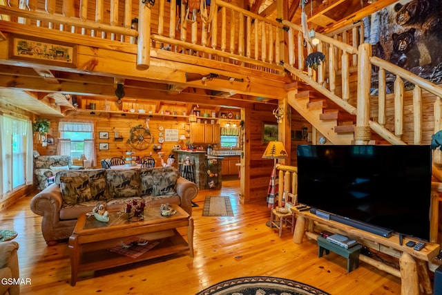living area with wood walls, light wood-style floors, stairs, and a towering ceiling