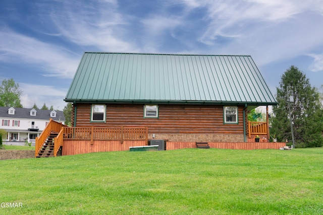 back of house featuring stairway, central AC, a lawn, log siding, and metal roof