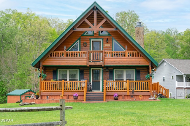 log home featuring log exterior, a front yard, a balcony, and a chimney