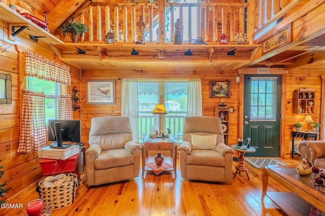 living room featuring wooden walls, a towering ceiling, beam ceiling, and hardwood / wood-style floors