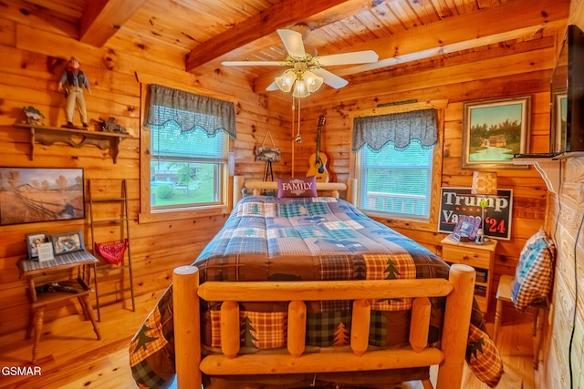 bedroom with multiple windows, beamed ceiling, wood-type flooring, wooden walls, and wood ceiling